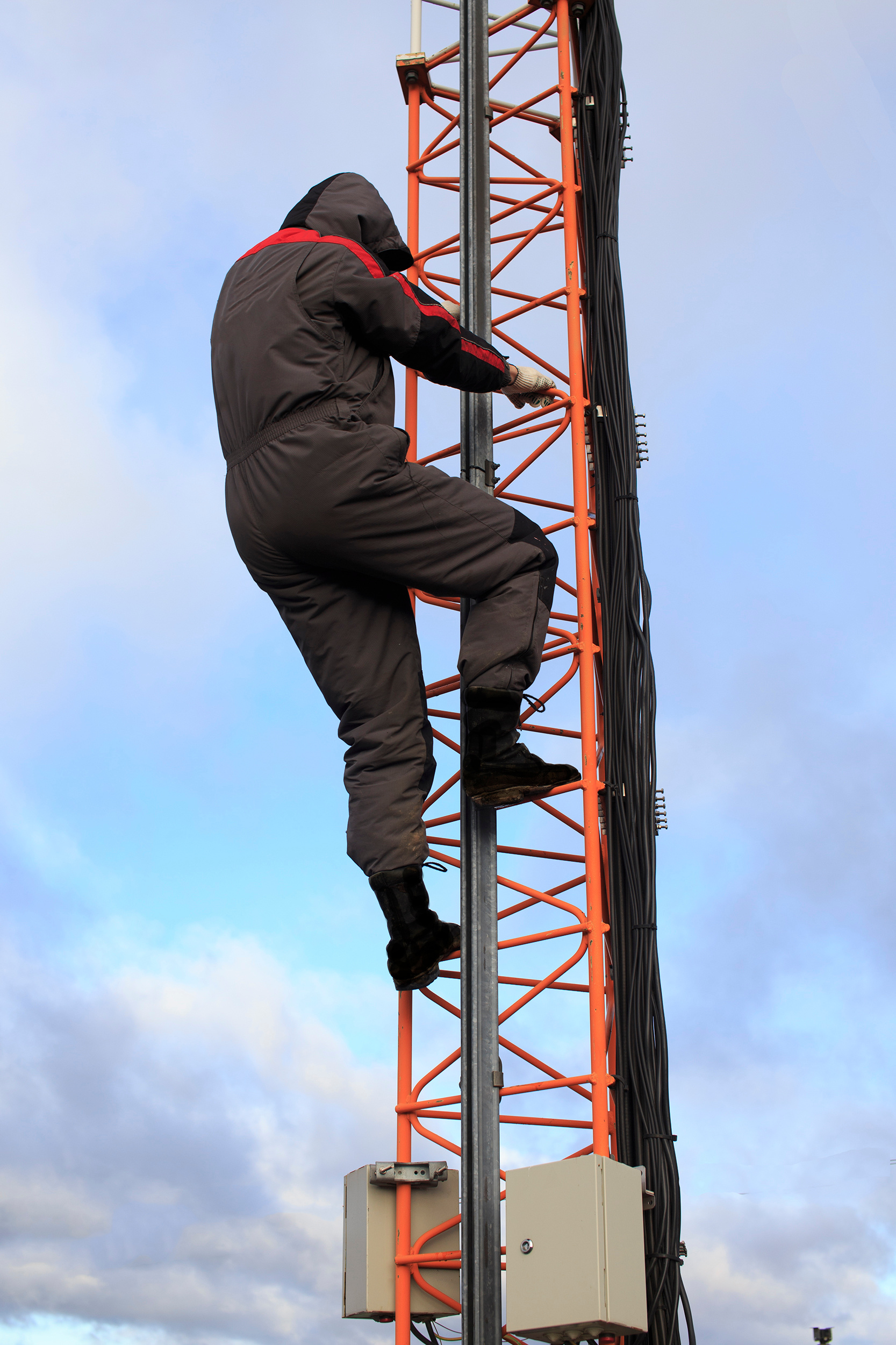 A worker climbs a telecommunication tower without a safety harness and safety equipment.